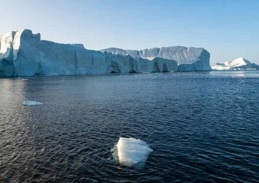 Isklump i Isfjorden foran isfjell ved Ilulissat, Grønland.
