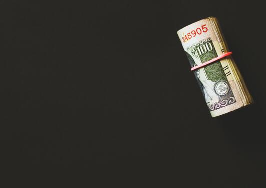 Penger i en rull på svart bakgrunn