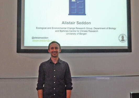 Alistair Seddon standing before the title slide of his lecture called The Ecological Time Machinee