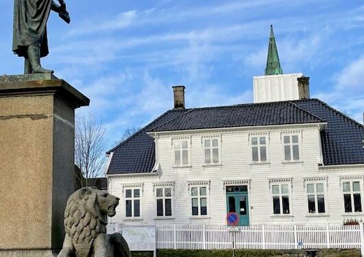 Foto av bygningen som er Langesgate 1-3, med museplassen og Cristies statuen i forgrunnen. 