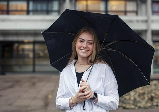Student Tuva Småland Hagland med paraply forran Realfagsbygget