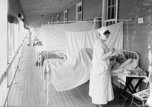 mann blir behandlet på walter reed sykehus i washington for spanskesyken. Sykepleier står ved siden av. Sort hvitt foto. 