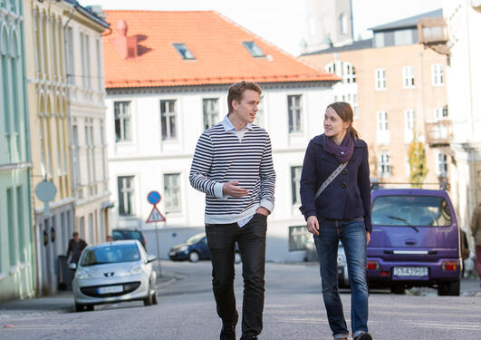 To studenter spaserer gjennom gatene, med SV-bygget i bakgrunnen.