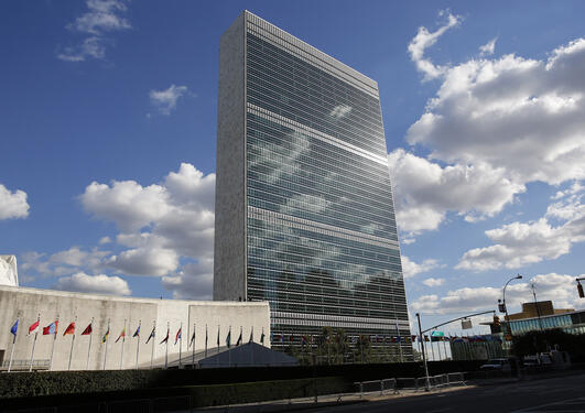 Photo of the United Nations building in New York, with clouds and the sun reflecting. Used to illustrate article about science diplomacy.