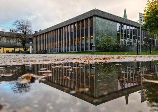 Bilde fra bakken i vannpytt som speiler HF-biblioteket (baksiden)