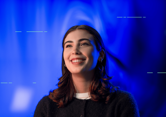 Smilende ung kvinne med blå bakgrunn.