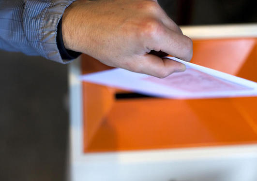 Bilde av hånd som legger stemmeseddel i urne