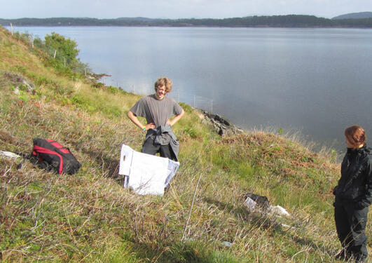 Two students surveying heathland vegetation next to a fjord