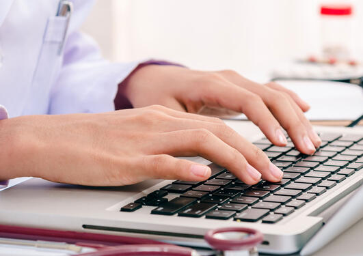 a doctor writing on a laptop.